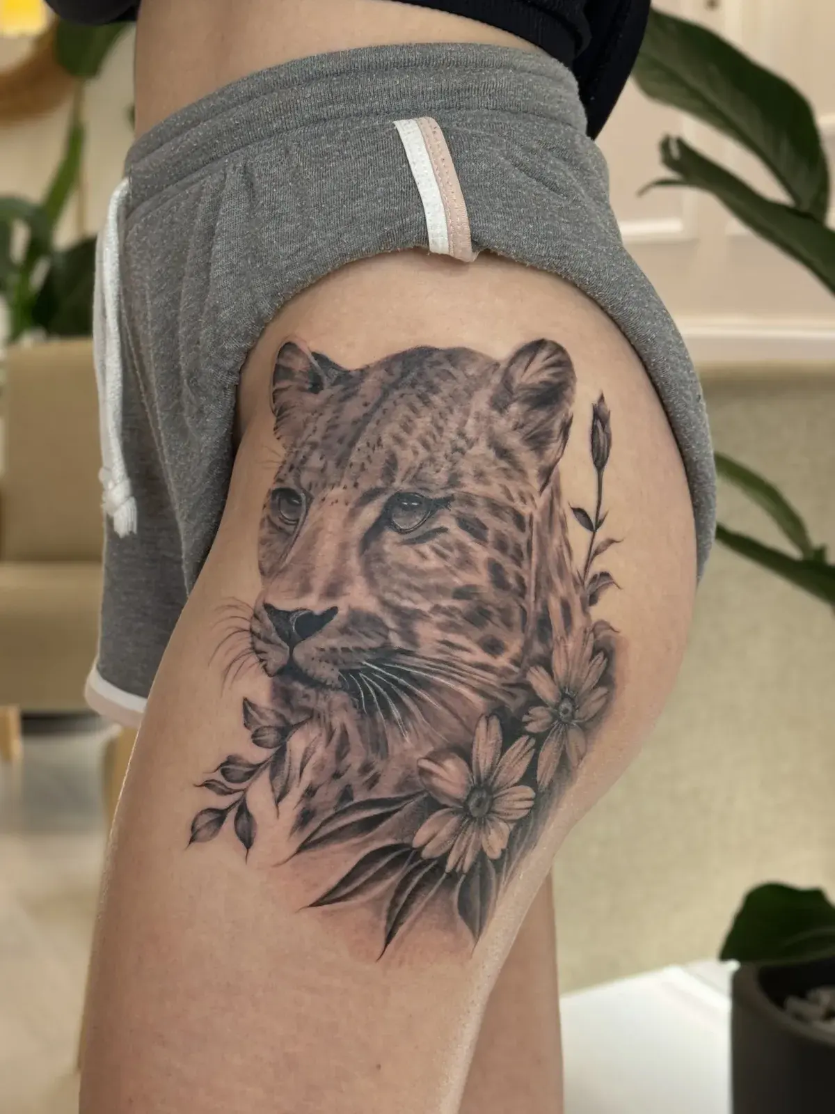 Bacakta leopar ve çiçeklerden oluşan realizm dövme